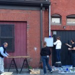 Community members clean up and paint the wall with chalkboard paint.